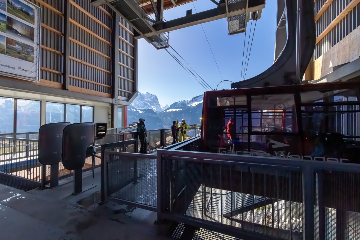 eine Bergbahn in die Leute Einsteigen mit den Bergen im Hintergrund